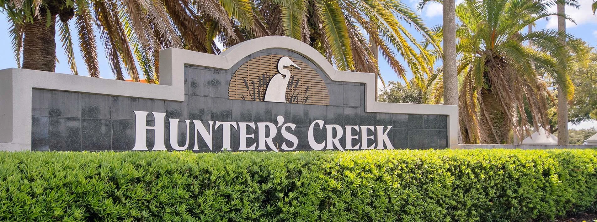 Hunters Creek community entrance with landscaping and palm trees